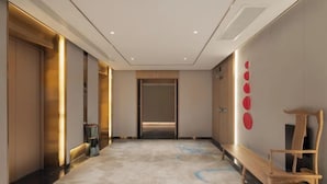 Un pasillo moderno de hotel con un banco, una silla de madera y una pared con adornos circulares.