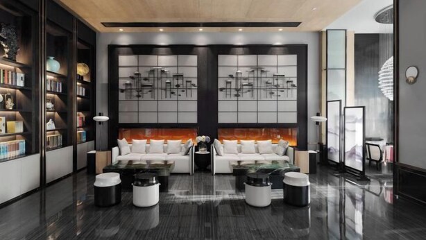 Un lobby moderno con una zona de estar central, una estantería y un panel decorativo en la pared.