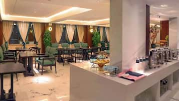 A hotel lobby with seating arrangements, a reception desk, and a coffee station.