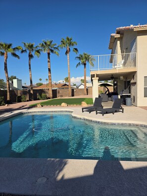 A swimming pool with lounge chairs, palm trees, and a building with a balcony. - Spacious 5-bedroom house in Charming Mesa with Sparkling Heated Pool (Mesa)