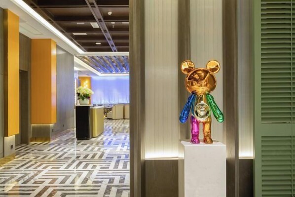 Un hall d’hôtel avec un sol à motifs, un comptoir d’accueil et une sculpture d’ours exposée.