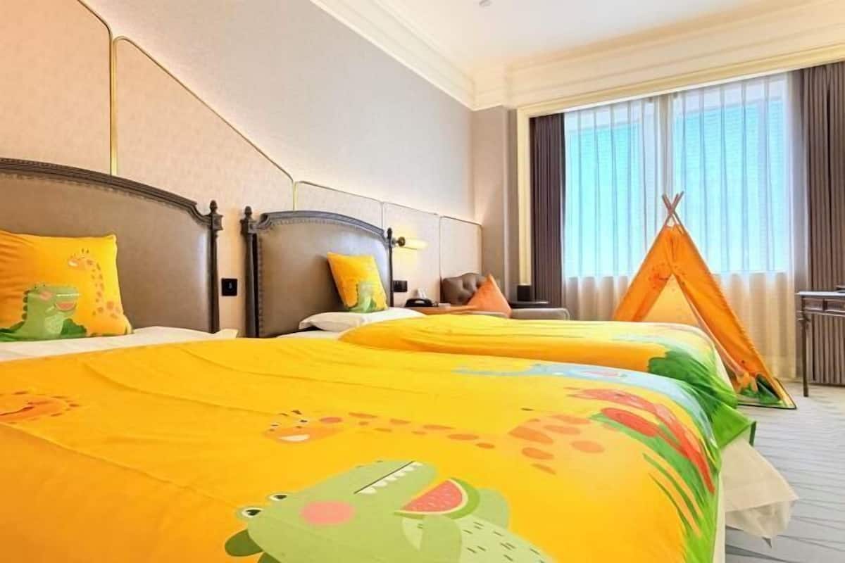 Camera d'albergo con due letti, una grande finestra e una decorazione a tenda indiana.