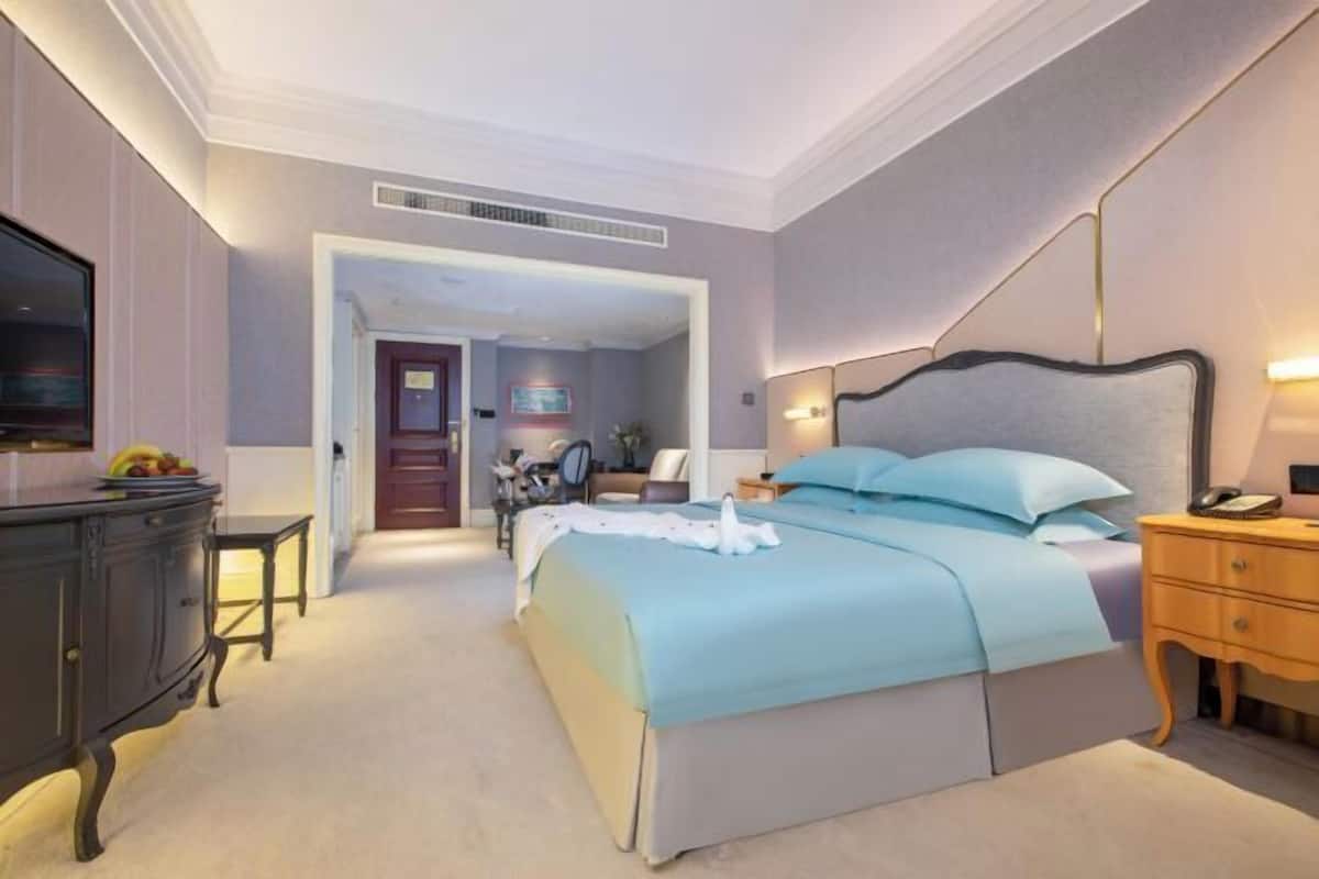 Una camera d'albergo con un letto, un comodino, una lampada e un televisore su un mobile.