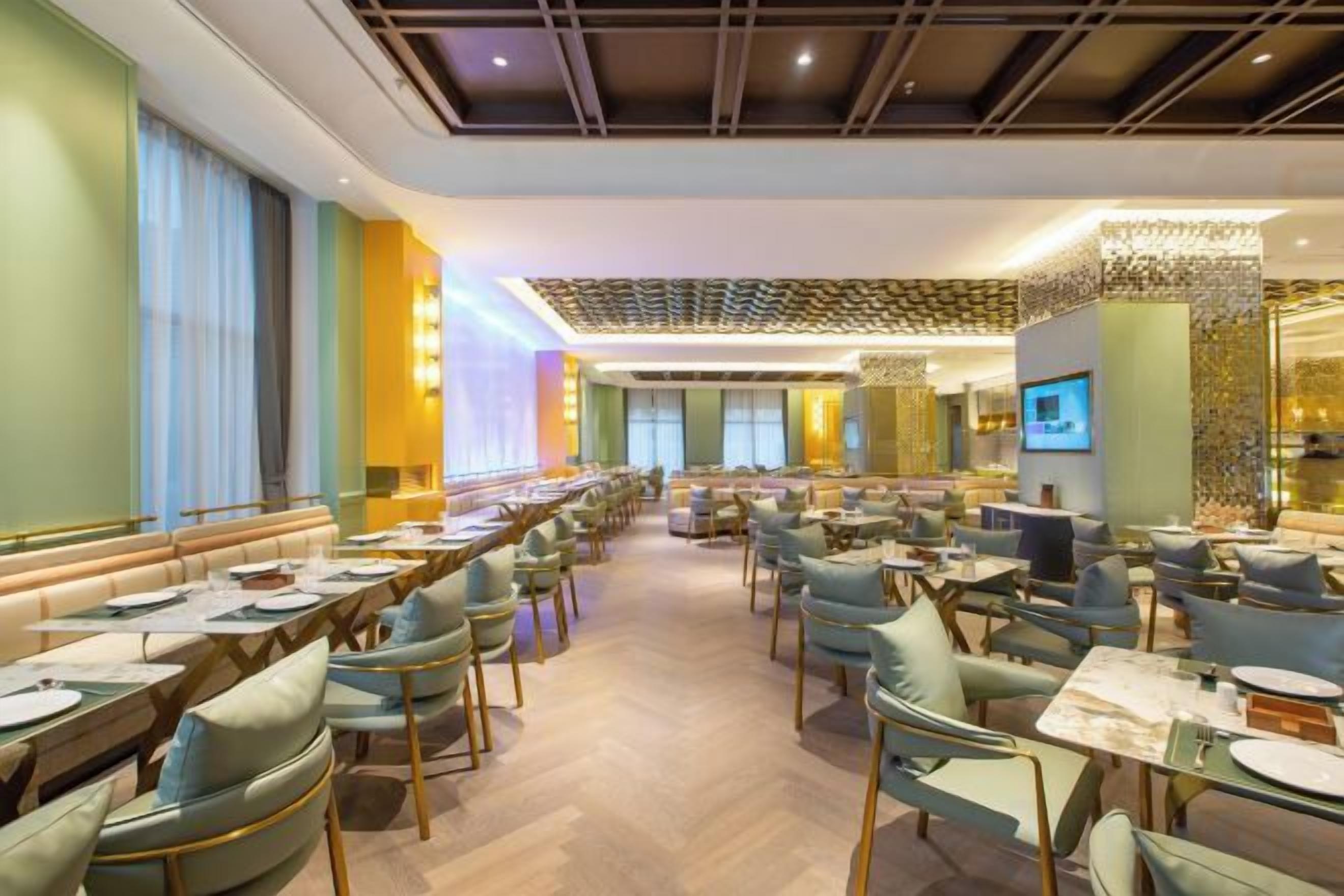 A spacious dining area with multiple tables and chairs, a long counter, and a modern ceiling design.