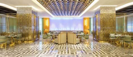 A spacious lobby with a patterned floor, a central seating area, and decorative wall panels.