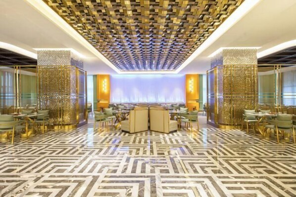 Un hall d’entrée spacieux, doté d’un sol à motifs, d’un espace salon central et de panneaux décoratifs sur les murs.