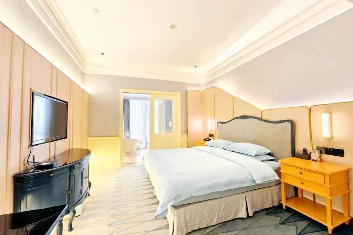 Una camera d'albergo con un letto, una televisione, un comodino e una cassettiera.