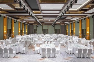 A large banquet hall with round tables and chairs, high ceilings, and modern lighting.