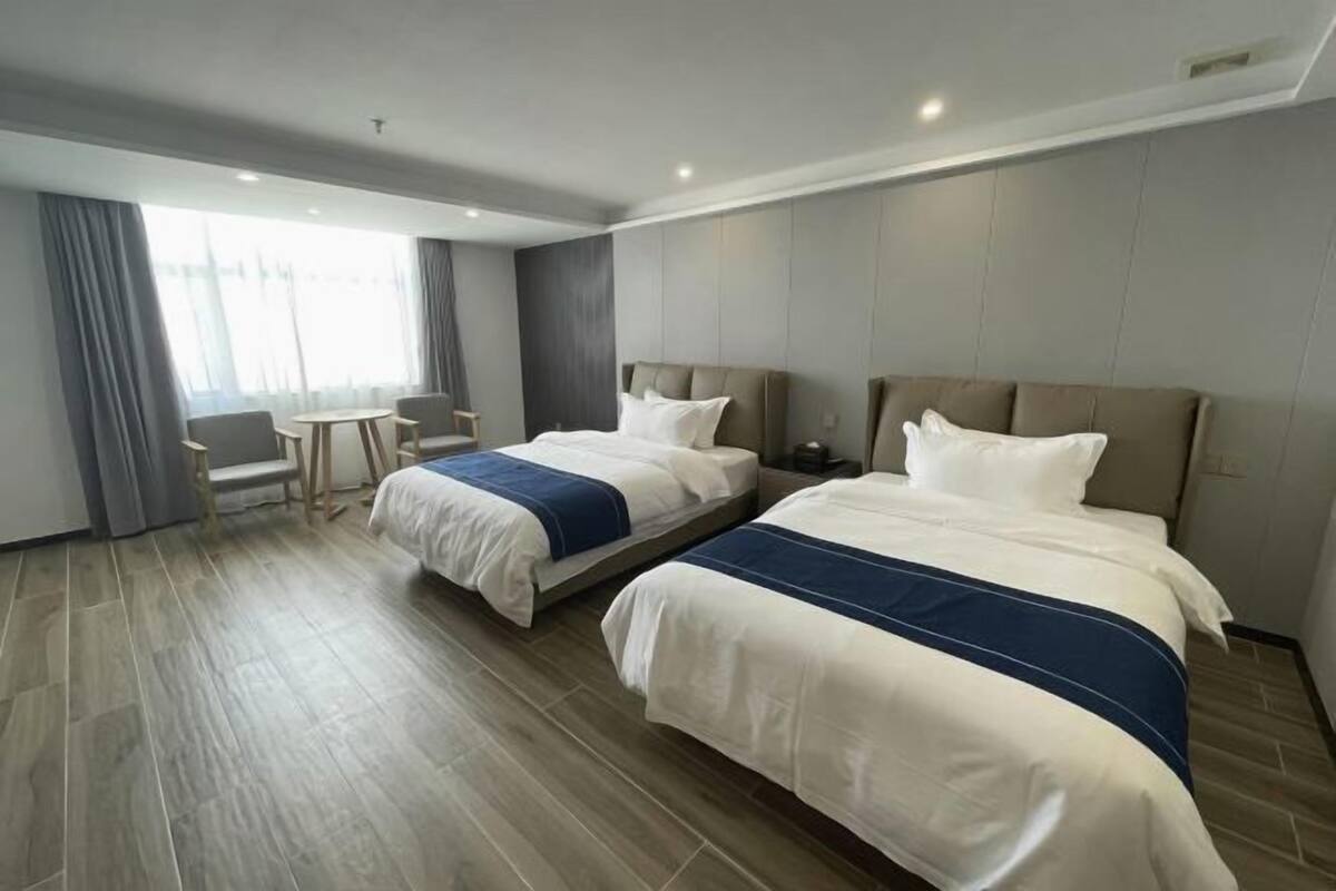 Ein Hotelzimmer mit zwei Betten, einem kleinen Tisch und einem Stuhl.