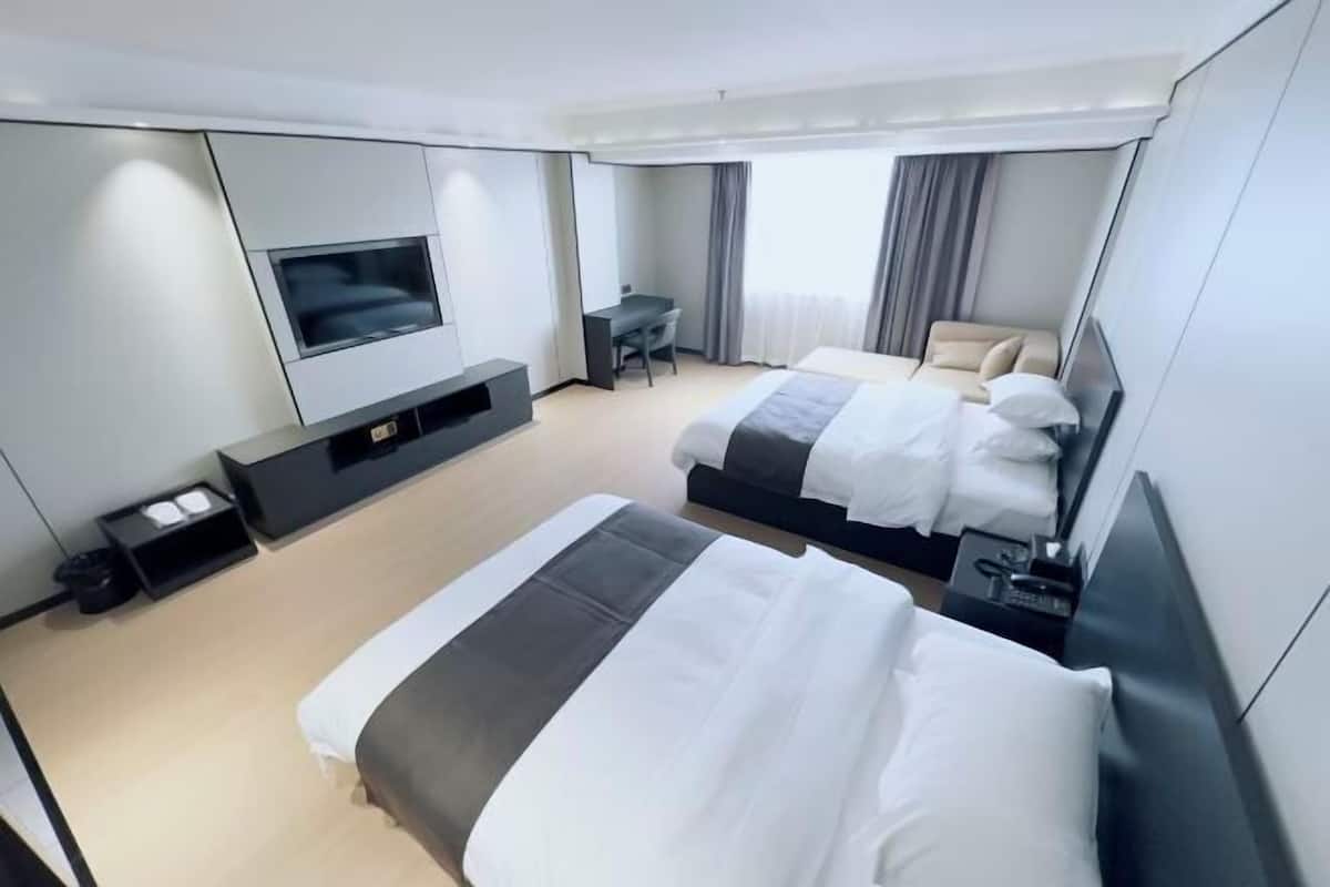 Ein modernes Hotelzimmer mit einem großen Bett, einem Schreibtisch, einem Fernseher und einer Sitzecke.