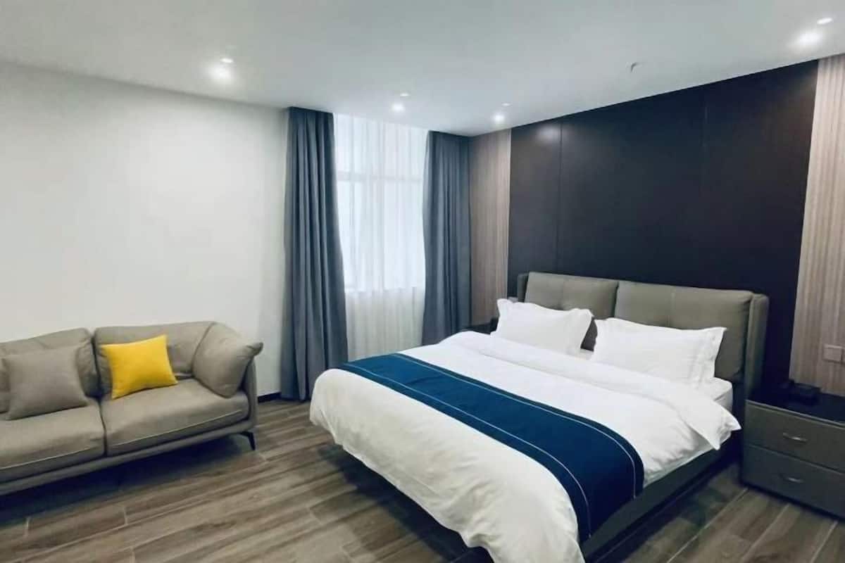 Ein modernes Hotelzimmer mit einem großen Bett, einer Couch und einem Nachttisch.