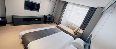 Een moderne hotelkamer met een groot bed, een bureau, een flatscreen televisie en een bank.
