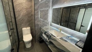 A modern bathroom with a marble vanity, a toilet, and a large mirror. - Langquan Bay Hotel (Guangzhou South Railway Station) (Guangzhou)