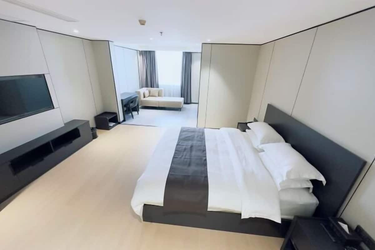 Ein modernes Hotelzimmer mit einem großen Bett, einem Flachbildfernseher, einer Couch und einem Schreibtisch.