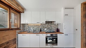 A modern kitchen with white cabinets, a brick backsplash, and a wooden countertop.