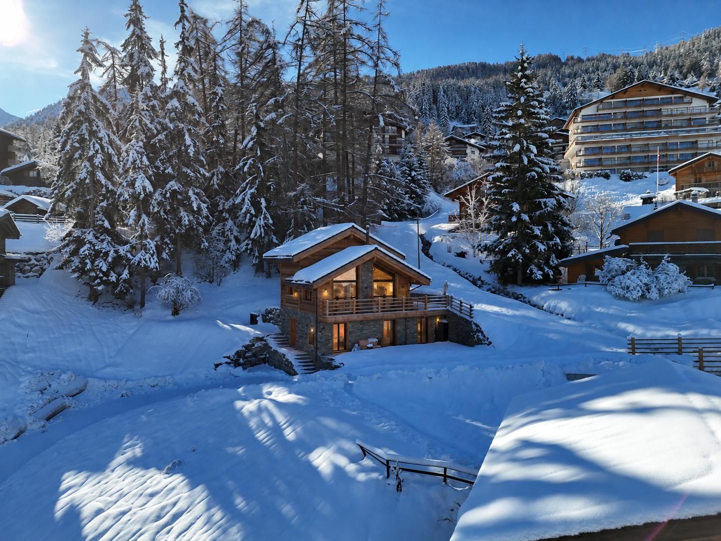 A snow-covered lodge with a wooden exterior, a stone foundation, and a balcony overlooking a snowy landscape.