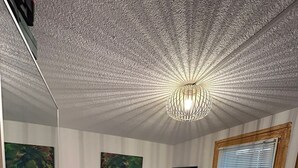 Una habitación pequeña con una cama, un escritorio, una silla, un televisor y dos cuadros en la pared.