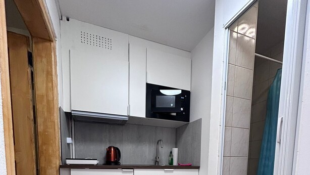 Cocina compacta con gabinetes blancos, microondas y cafetera.
