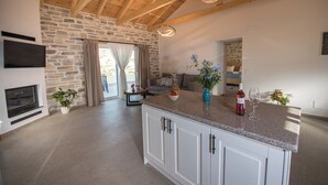 A spacious kitchen with a large island, stone walls, and wooden beams.