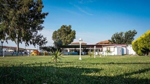 A grassy area with a playground, picnic tables, and a small building with a red roof. - Korfez Pansiyon (Ayvalik)