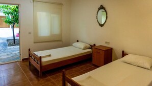 A small room with a bed, a nightstand, a mirror, and a window. - Korfez Pansiyon (Ayvalik)