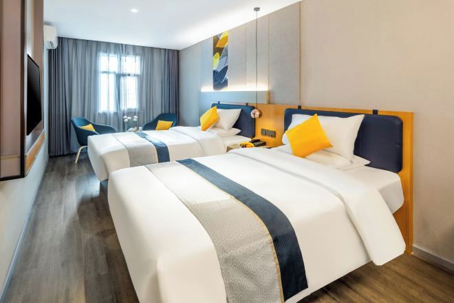 A hotel room with two beds, a TV, a desk, and a chair.