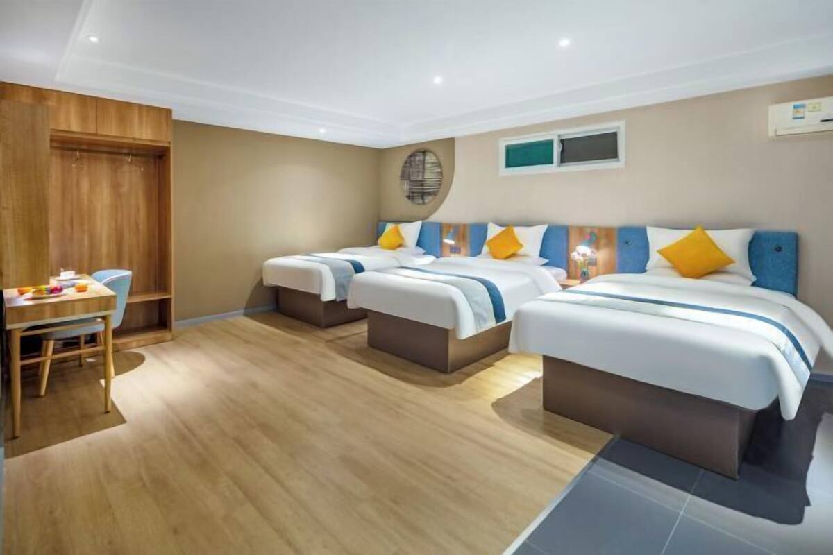 A hotel room with two beds, a wooden desk, and a chair.