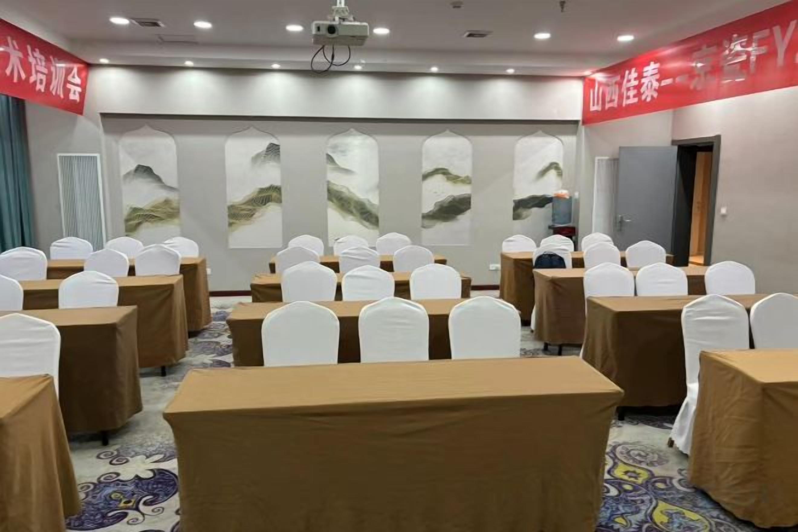 A conference room with tables and chairs, a projector, and a large screen.