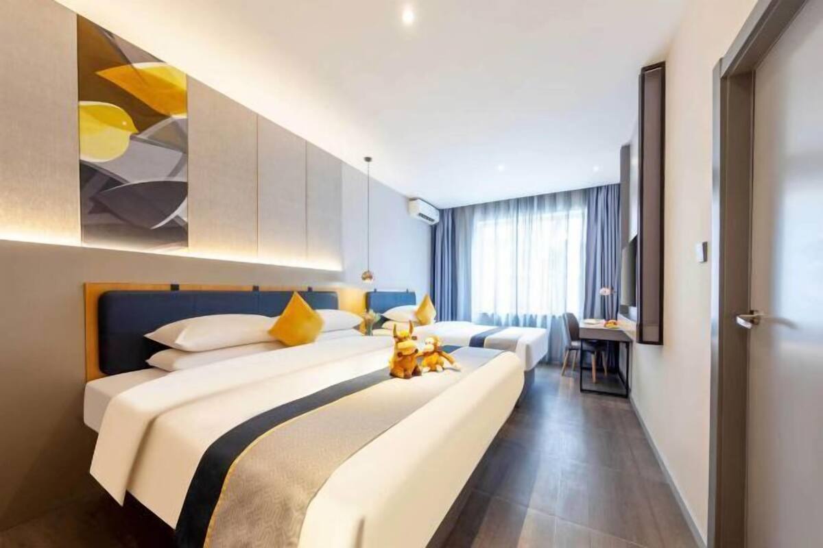 A modern hotel room with a large bed, a desk, and a view of the city.