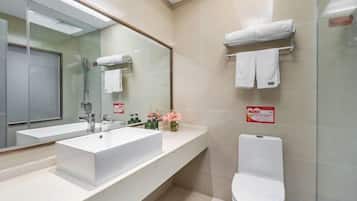 A modern bathroom with a large mirror, a white sink, and a toilet.
