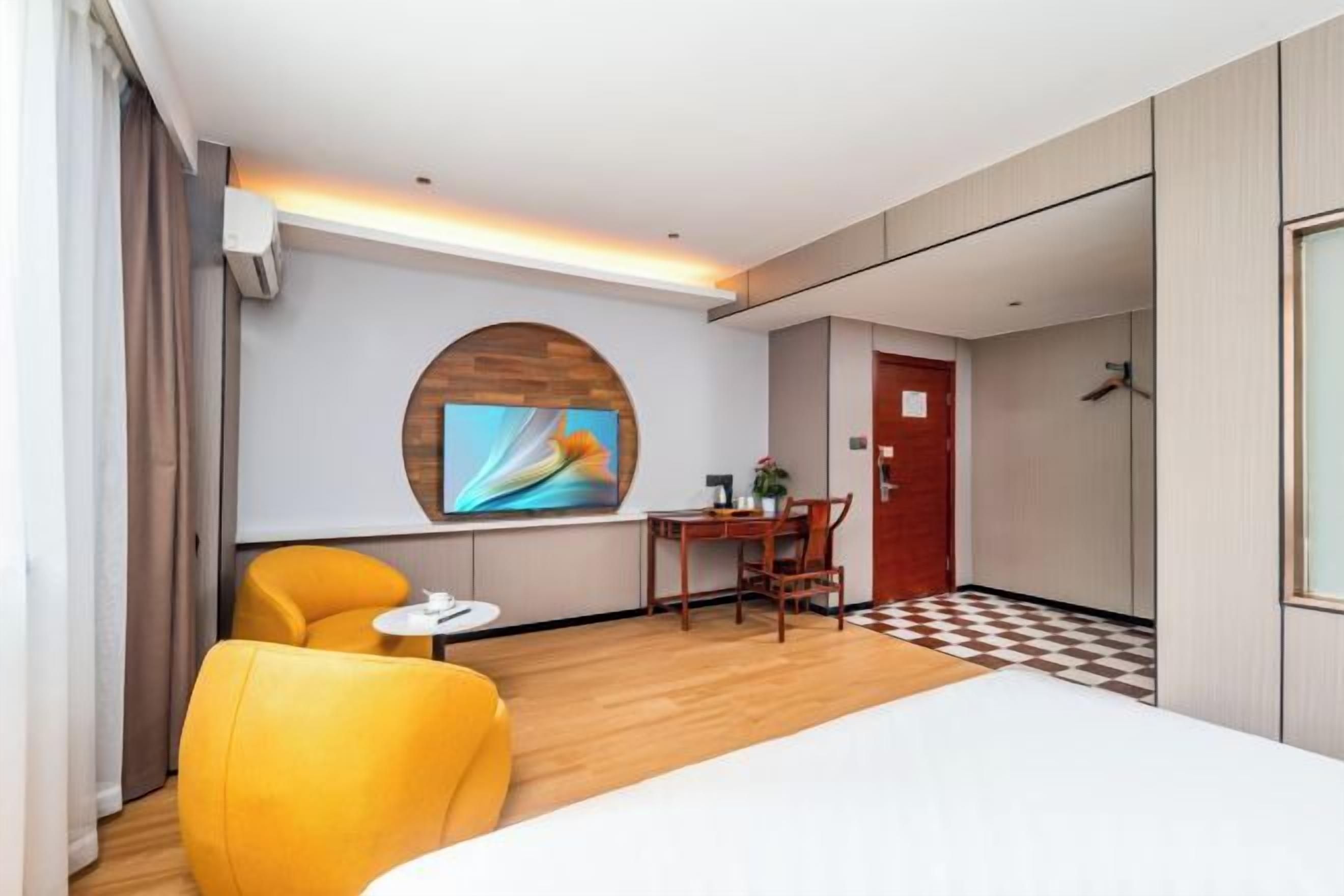 Quarto de hotel com cama, televisão, escrivaninha e cadeira.
