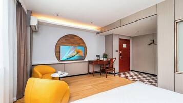 Quarto de hotel com cama, televisão, escrivaninha e cadeira.