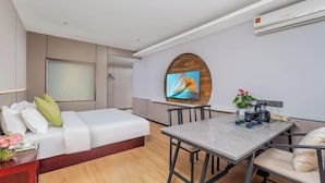 A modern hotel room with a bed, a TV mounted on a wooden wall, a dining table with chairs, and an air conditioning unit. - Yiting Four Seasons Hotel (Shanghai Lujiazui Pudian Road Subway Station) (Shanghai)
