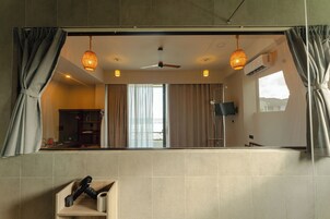 Un baño con un espejo grande, un ventilador de techo y dos luces colgantes.