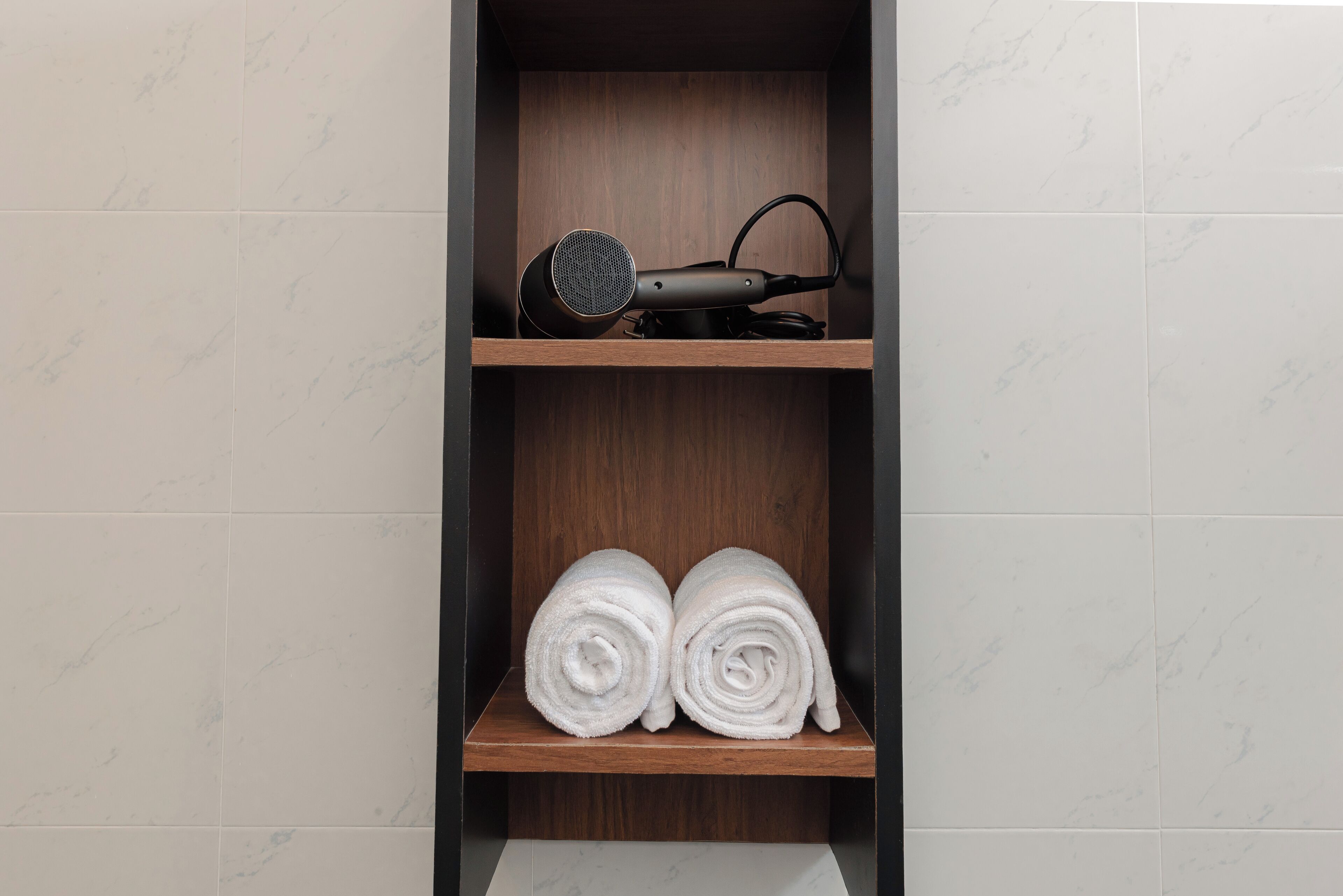 Un baño con un estante de madera que contiene un secador de pelo y toallas.