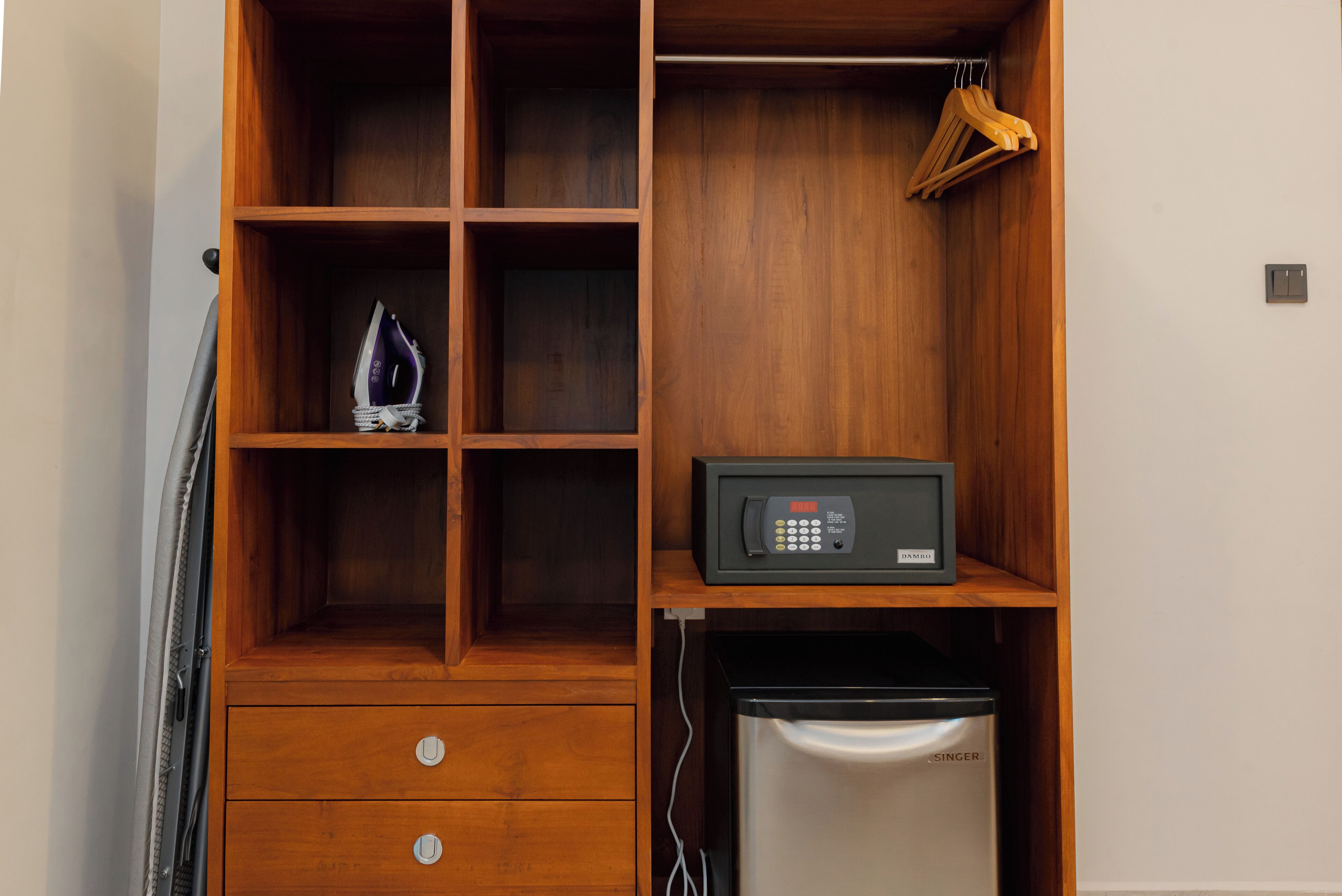 A wooden wardrobe with multiple compartments, a microwave, and a refrigerator.