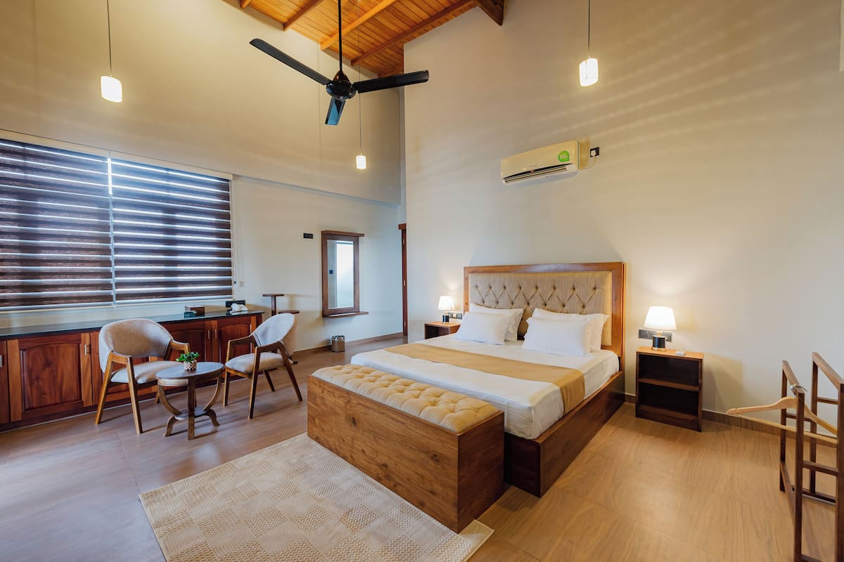 Un dormitorio espacioso con una cama grande, un cabecero de madera, un escritorio con una silla y una ventana con persianas.