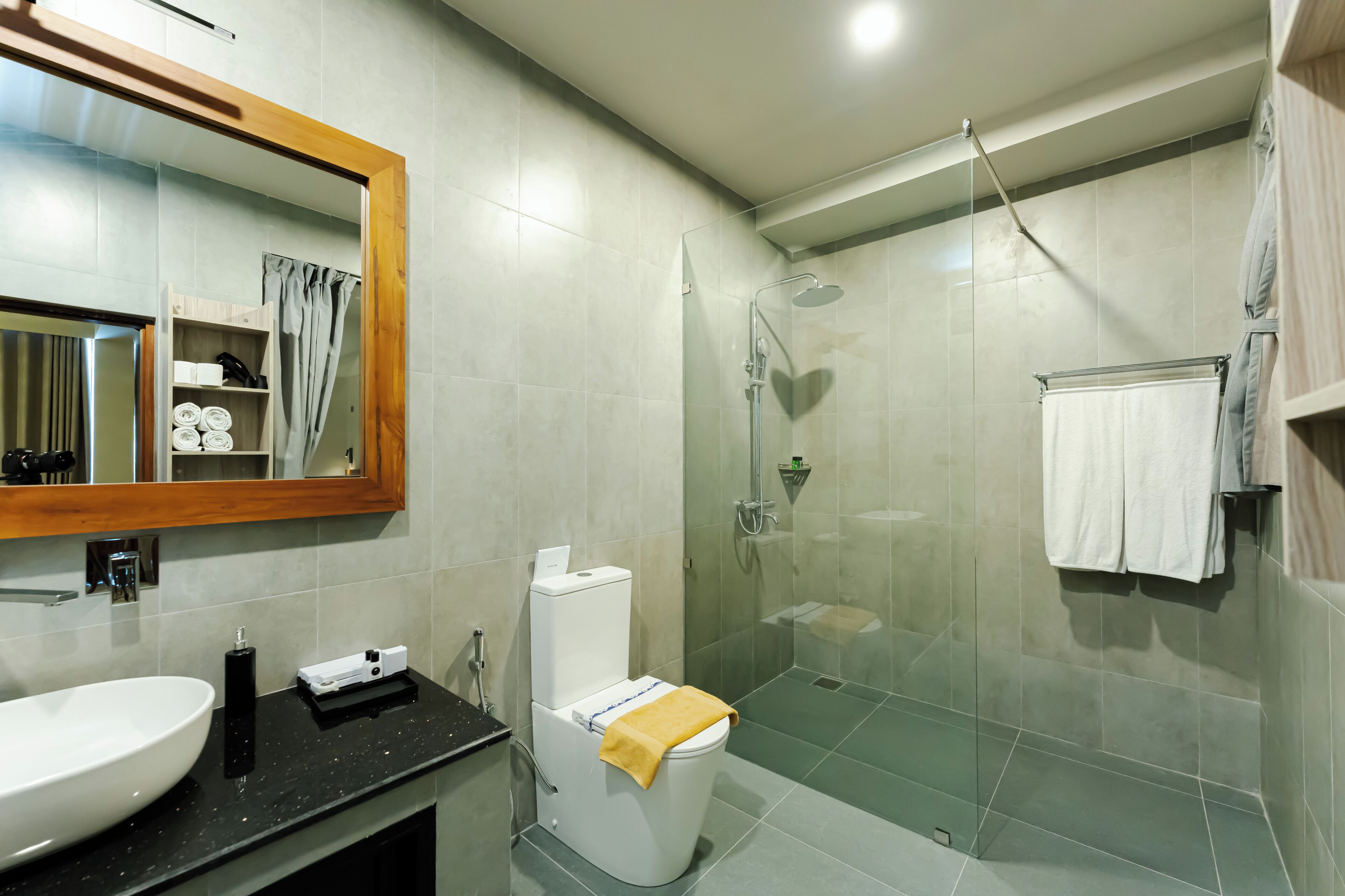 A bathroom with a large mirror, a sink, a toilet, a shower, and a towel rack.