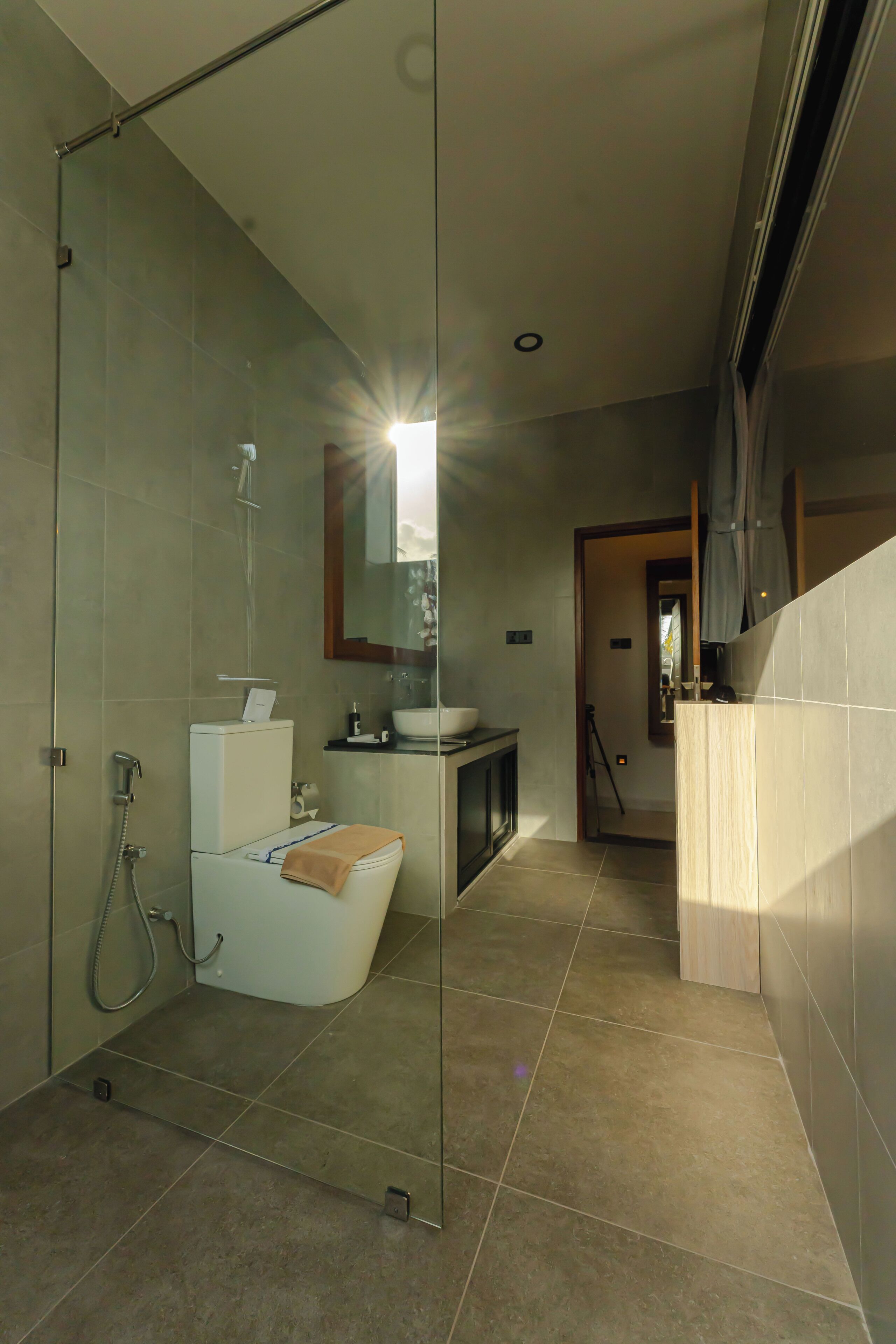 Un baño moderno con cabina de ducha de vidrio, inodoro y lavabo con espejo.