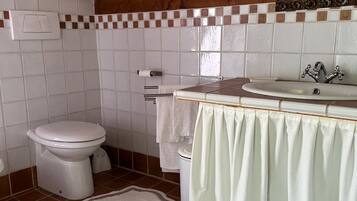 Une salle de bain avec des toilettes, un lavabo et un miroir. Il y a deux tapis sur le sol, chacun avec un motif textuel.