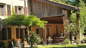 A two-story building with a covered patio area, outdoor seating, and a well-maintained garden. - BednBarchessa (Portogruaro)