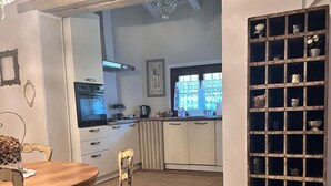 A kitchen with a dining area, featuring a rustic wooden table and chairs, a chandelier, and a decorative shelf with jars. - BednBarchessa (Portogruaro)