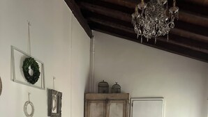 A bedroom with a large bed, a wardrobe, a chandelier, and a door. - BednBarchessa (Portogruaro)