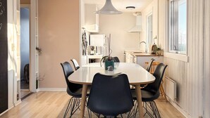 Un comedor moderno con una mesa redonda, sillas negras y una lámpara colgante.