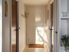 A hallway with a wooden floor, a white door, and a small rug at the entrance.