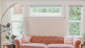 Une pièce comprenant un canapé, deux fauteuils, une petite table ronde, un lampadaire et un ventilateur de plafond.