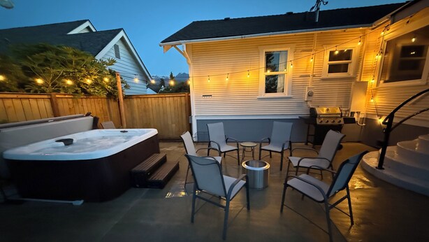 Un jardin avec un jacuzzi, des chaises de patio et un barbecue.