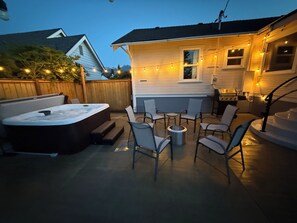 En trädgård med en bubbelpool, utemöbler och en grill.