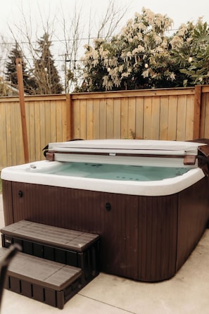 Un bain à remous avec une terrasse en bois et une clôture en bois en arrière-plan.
