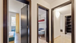 A corridor with a bunk bed, a door, and a shelf unit.